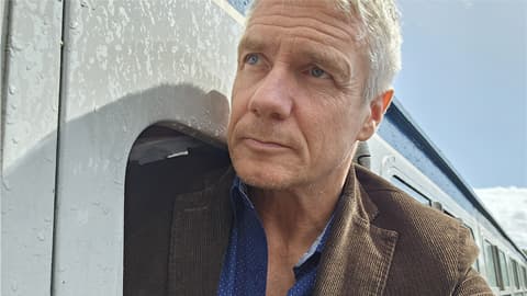 Professor Brian Haddock leans out of the window of a train carriage.